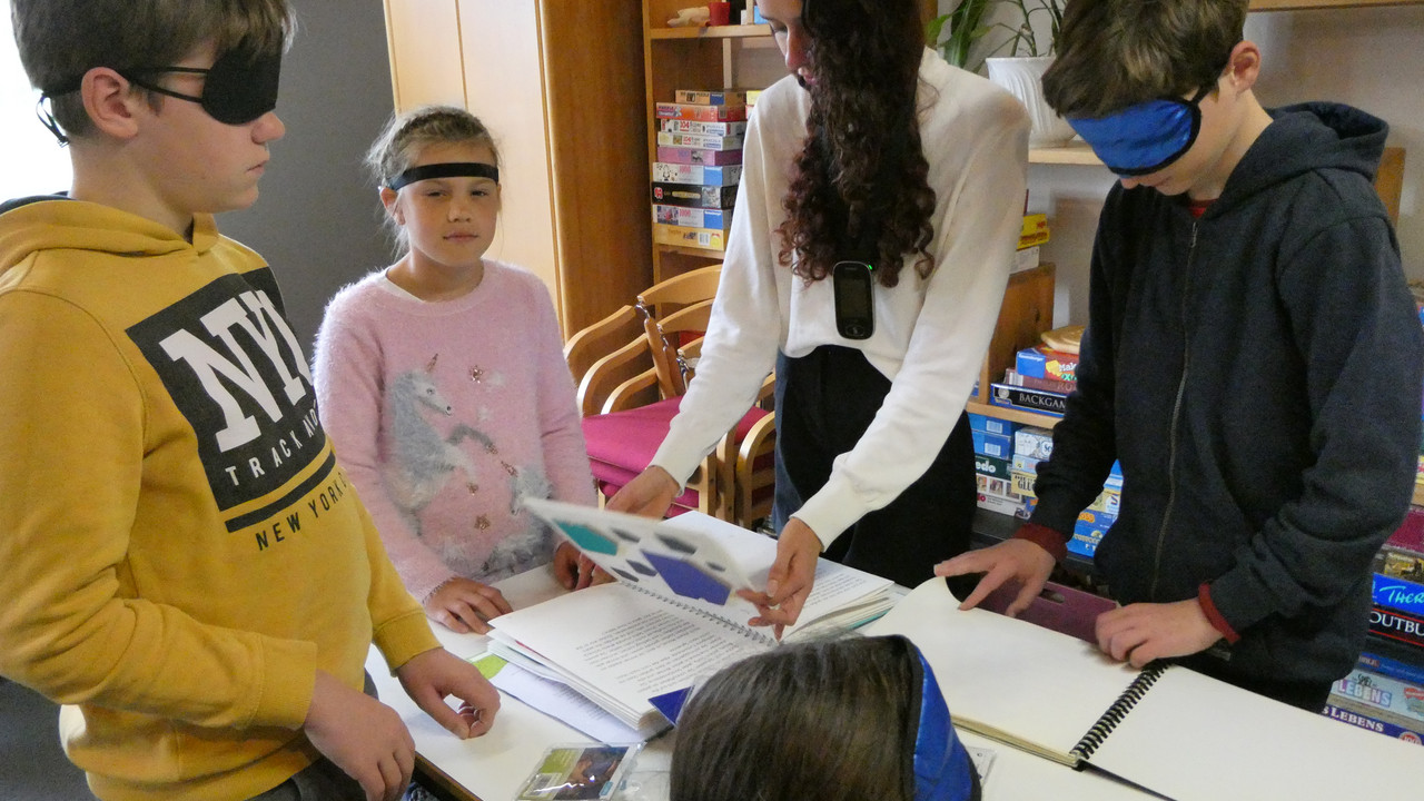 Schüler*innen versuchen mit Hilfe einer speziellen Blindenschrift zu lesen. 