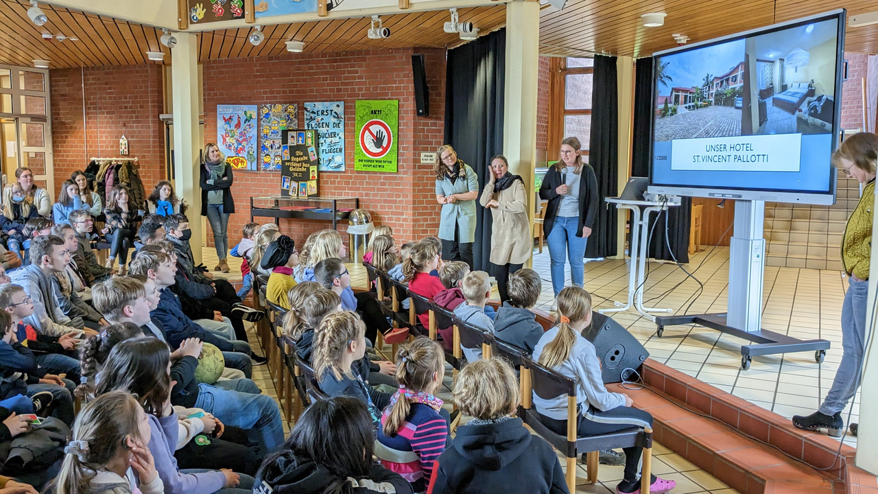 Schüler*innen und Lehrkräfte schauen Fotos im Foyer zu Ruanda