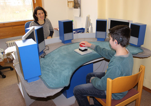 Lehrerin testet einen Schüler am Tisch in der Pädaudiologie