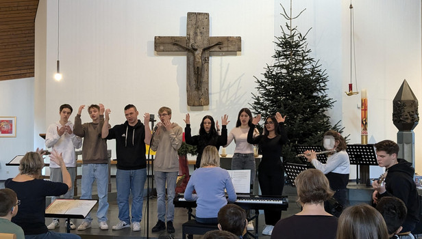 Schülerinnen und Schüler gebärden und musizieren am Altar in der Kirche