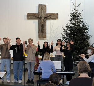 Schülerinnen und Schüler gebärden und musizieren am Altar in der Kirche