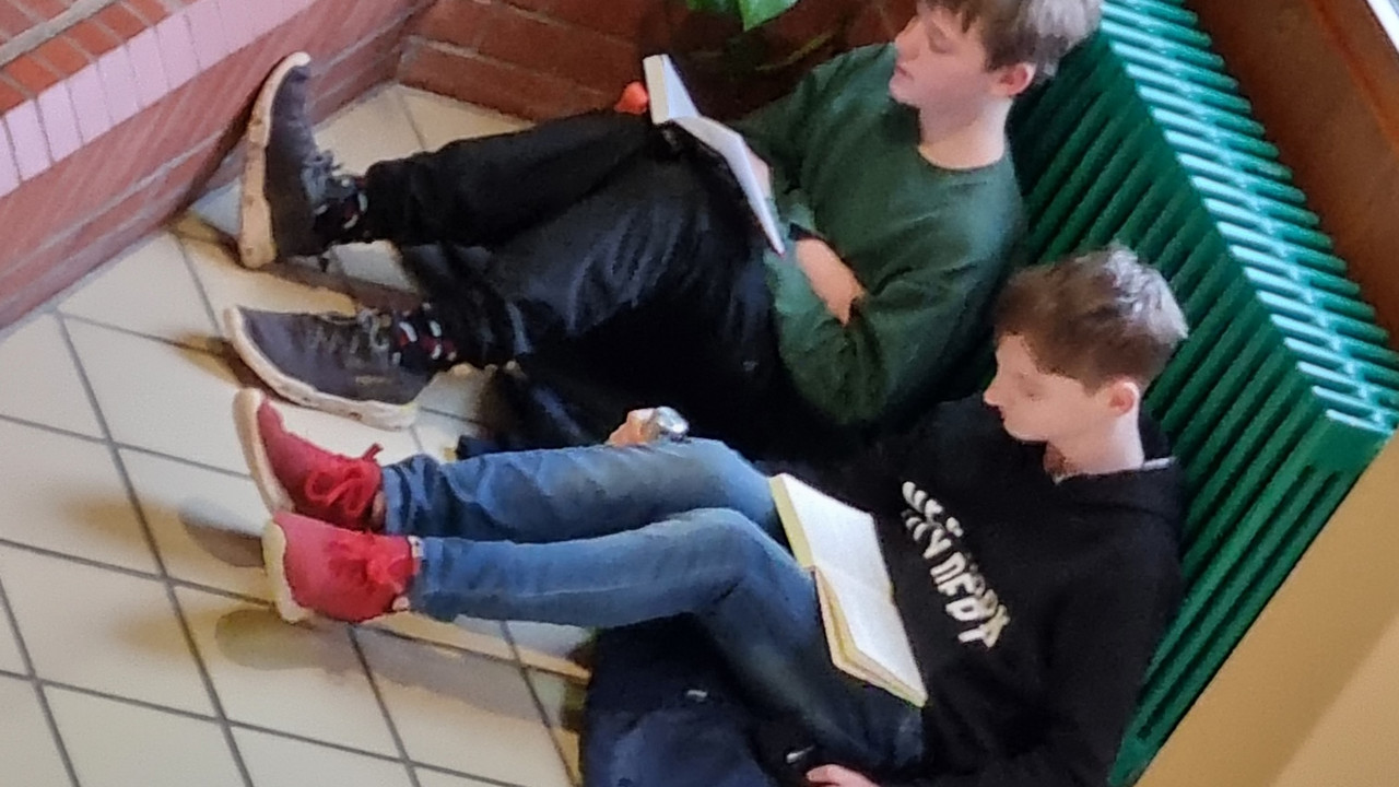 Schüler sitzen im Flur und lesen. 