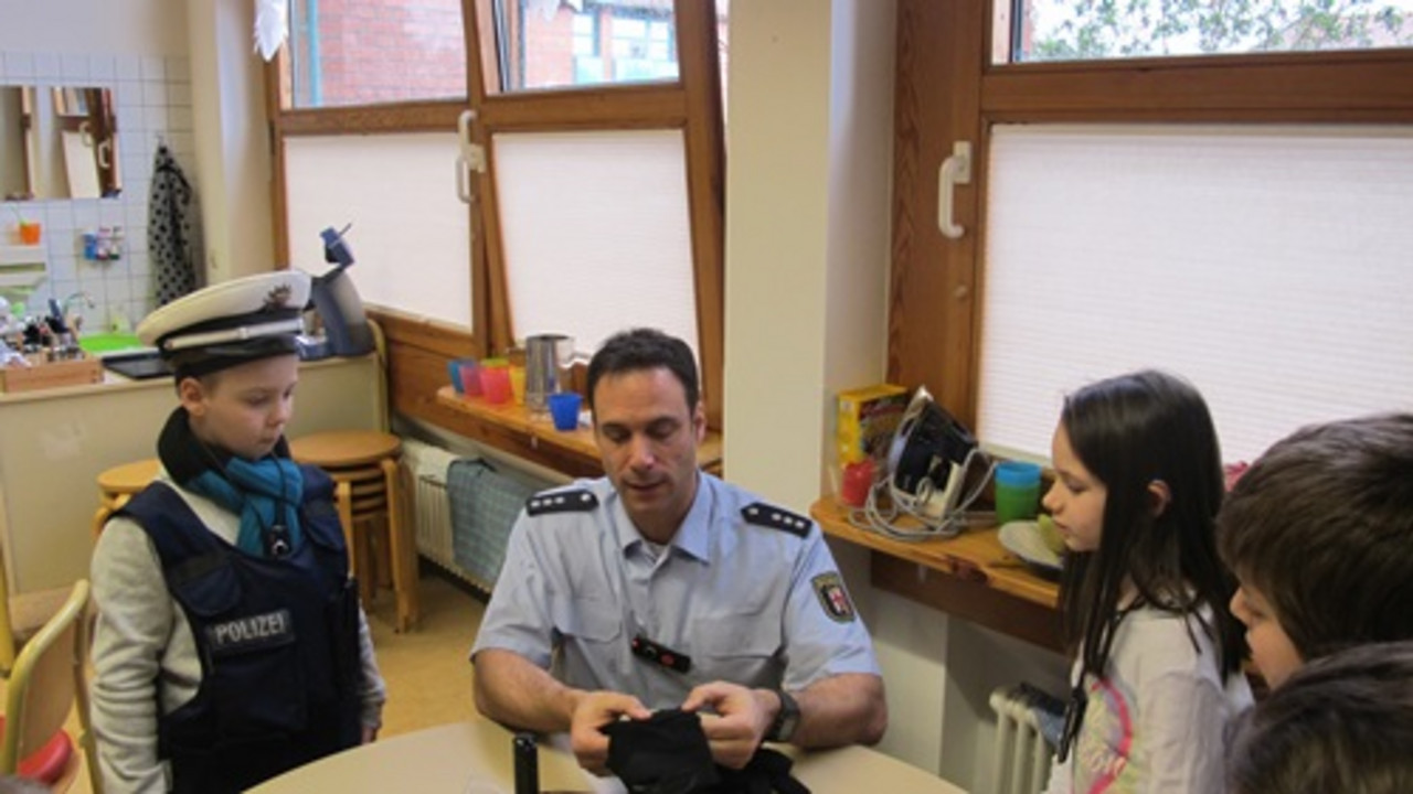 Polizist erklärt Schülern die Polizeiutensilien. 