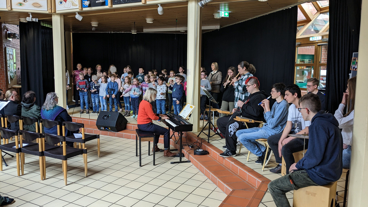 Schüler*innen singen und Schüler*innen spielen Instrumente auf der Bühne