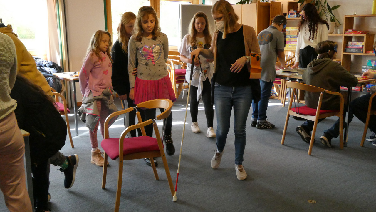 Schüler*innen üben das Gehen blind mit einem Taststock