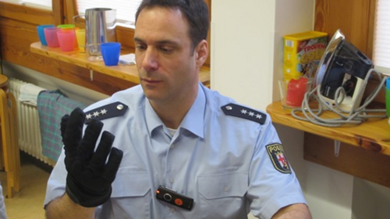 Polizist erklärt einen Schutzhandschuh. 