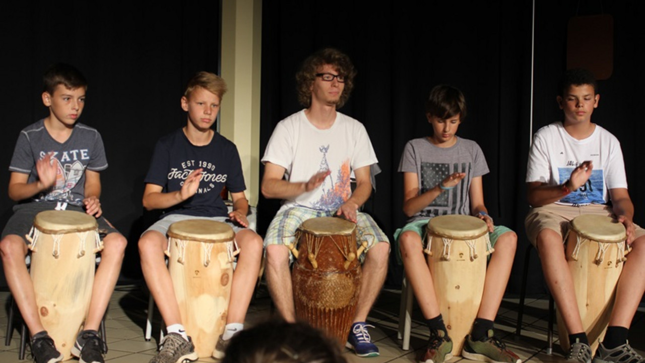Schüler und Lehrkraft trommeln. 