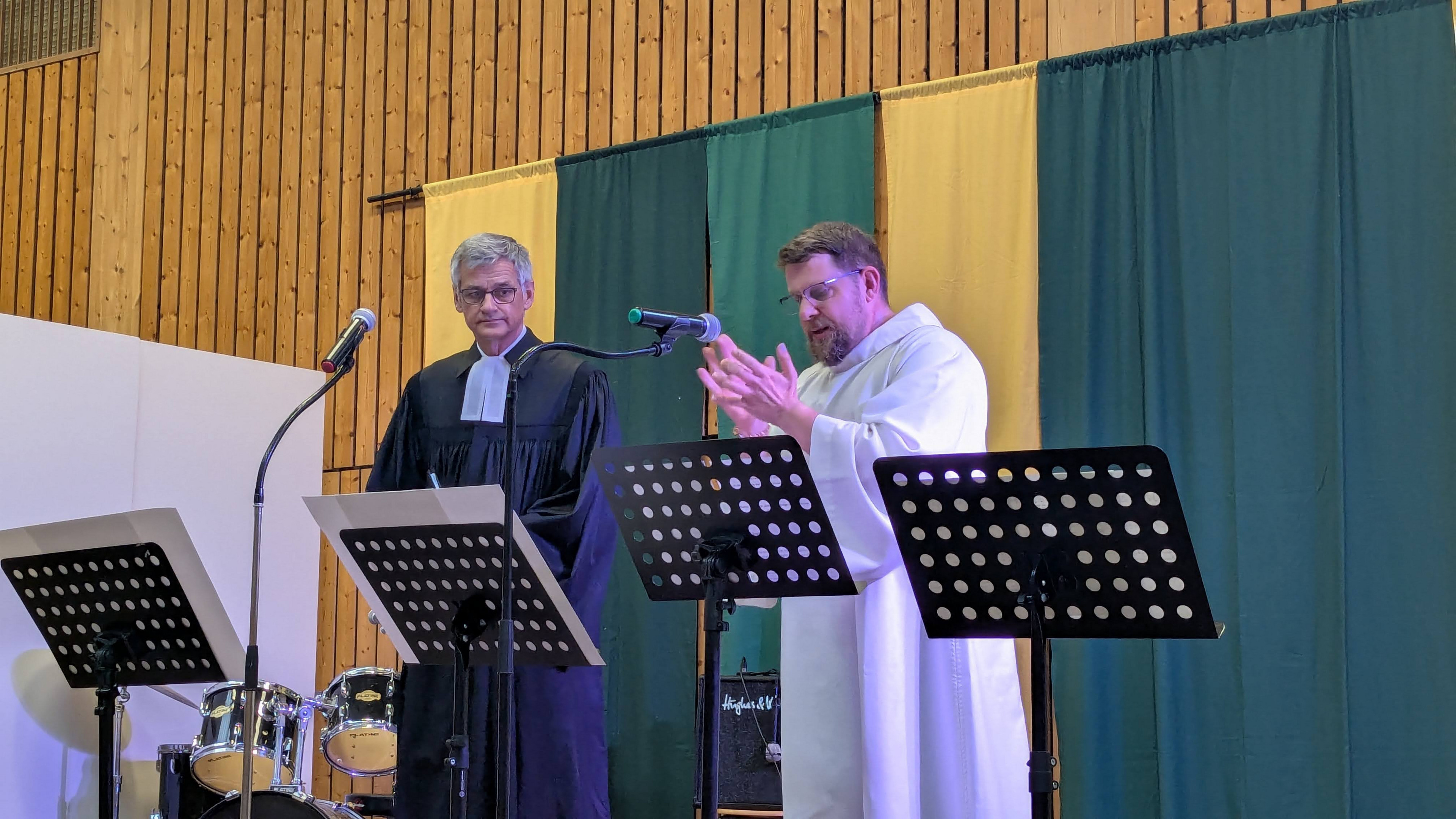 2 Pfarrer predigen in der Turnhalle im ökumenischen Gottesdienst