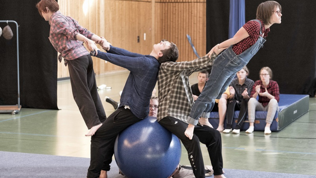 4 Schüler führen Kunststücke mit einem Gymnastikball auf. 