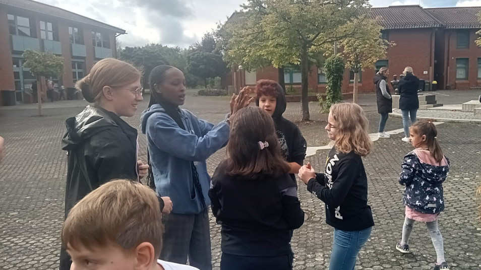 Gäste sprechen bzw. gebärden mit den Schülerinnen und Schülern auf dem Pausenhof.