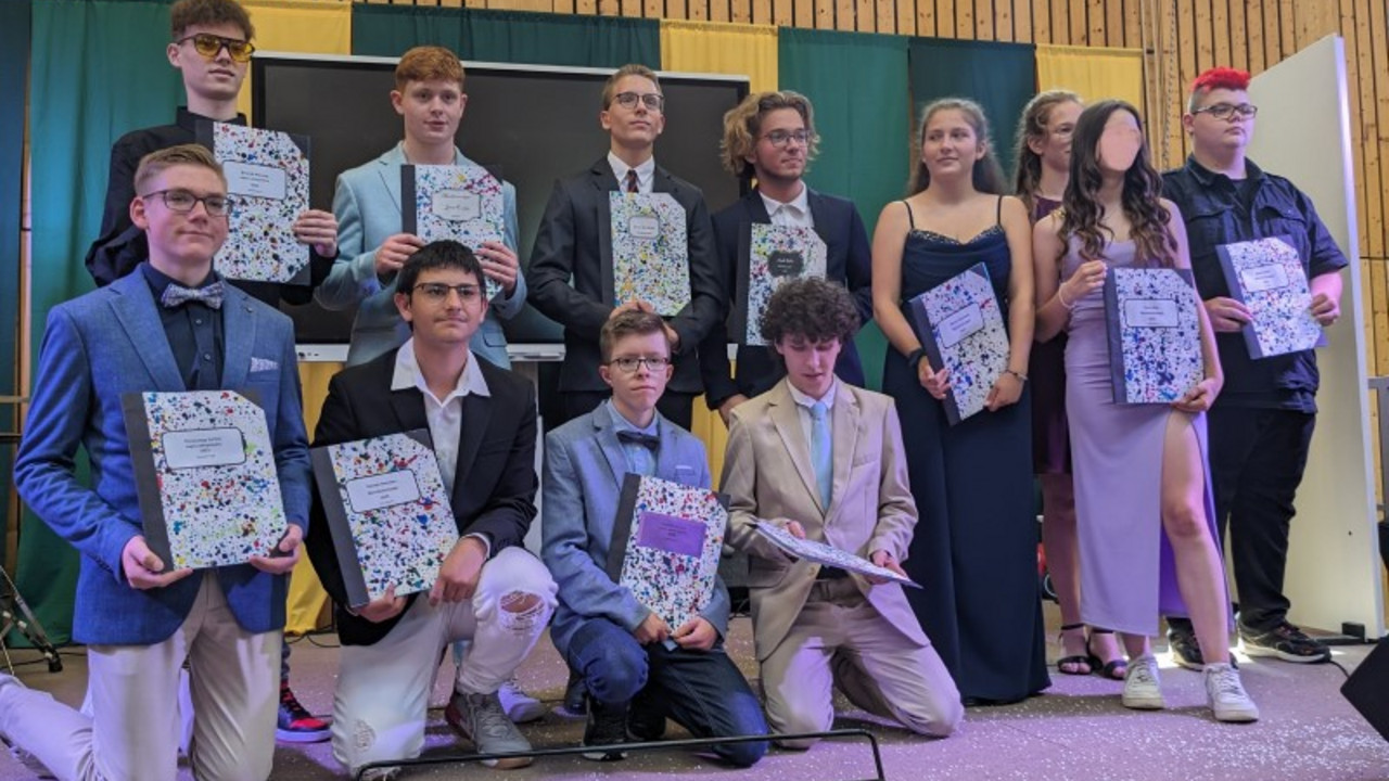 Schüler*innen mit ihren Zeugnissen auf der Bühne. 