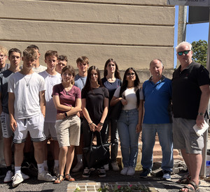 Gruppenfoto mit allen Akteuren vor den rosengeschmückten Stolpersteinen
