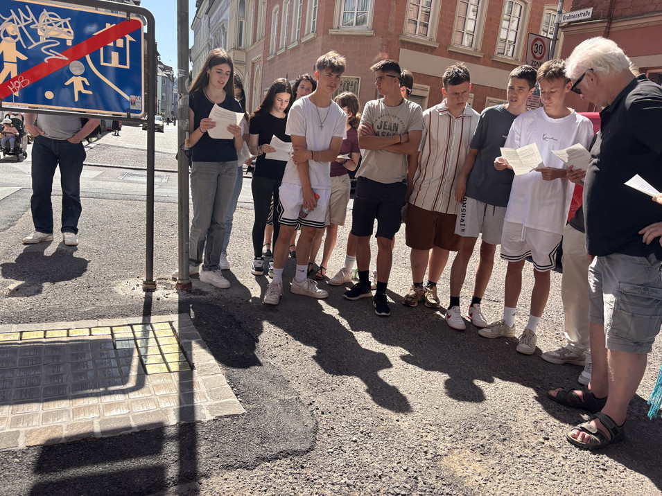 Schülerinnen und Schüler stehend in der Gruppe lesen die Namen der Opfer vor.