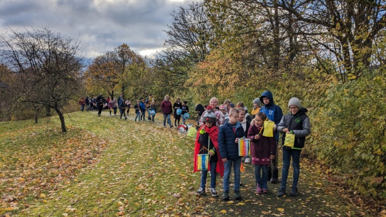 Schüler mit Laternen gehen über das Außengelände.