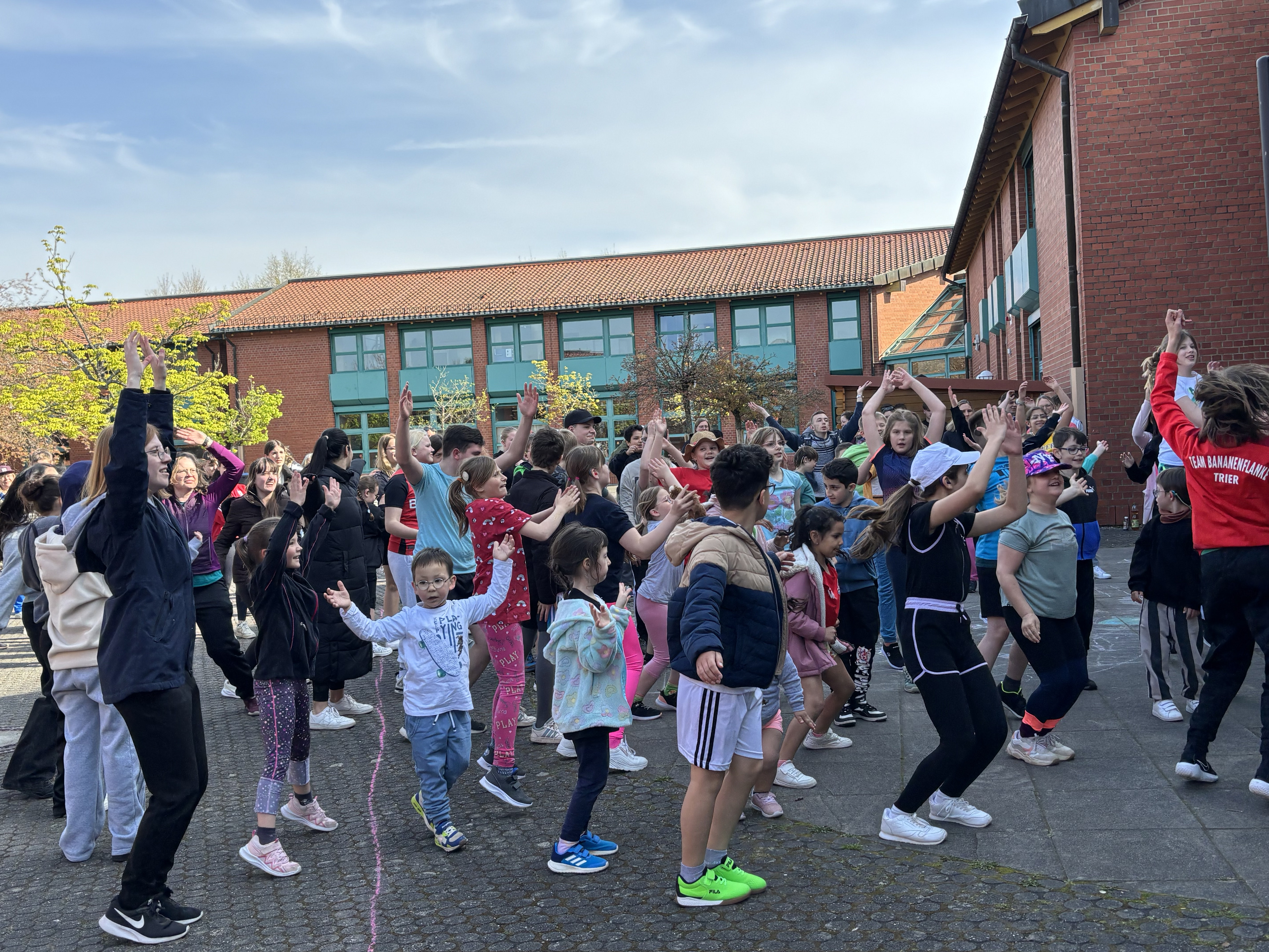 Viele Schüler applaudieren auf dem Schulhof. 
