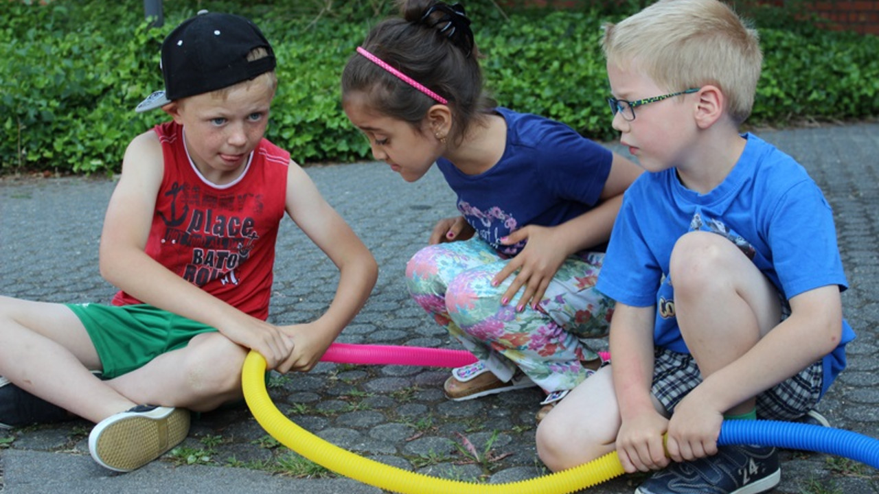 3 Schüler spielen mit Schlauch. 