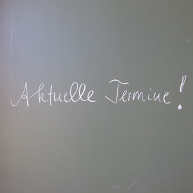Schriftzug Aktuelle Termine mit weißer Kreide auf Schultafel 