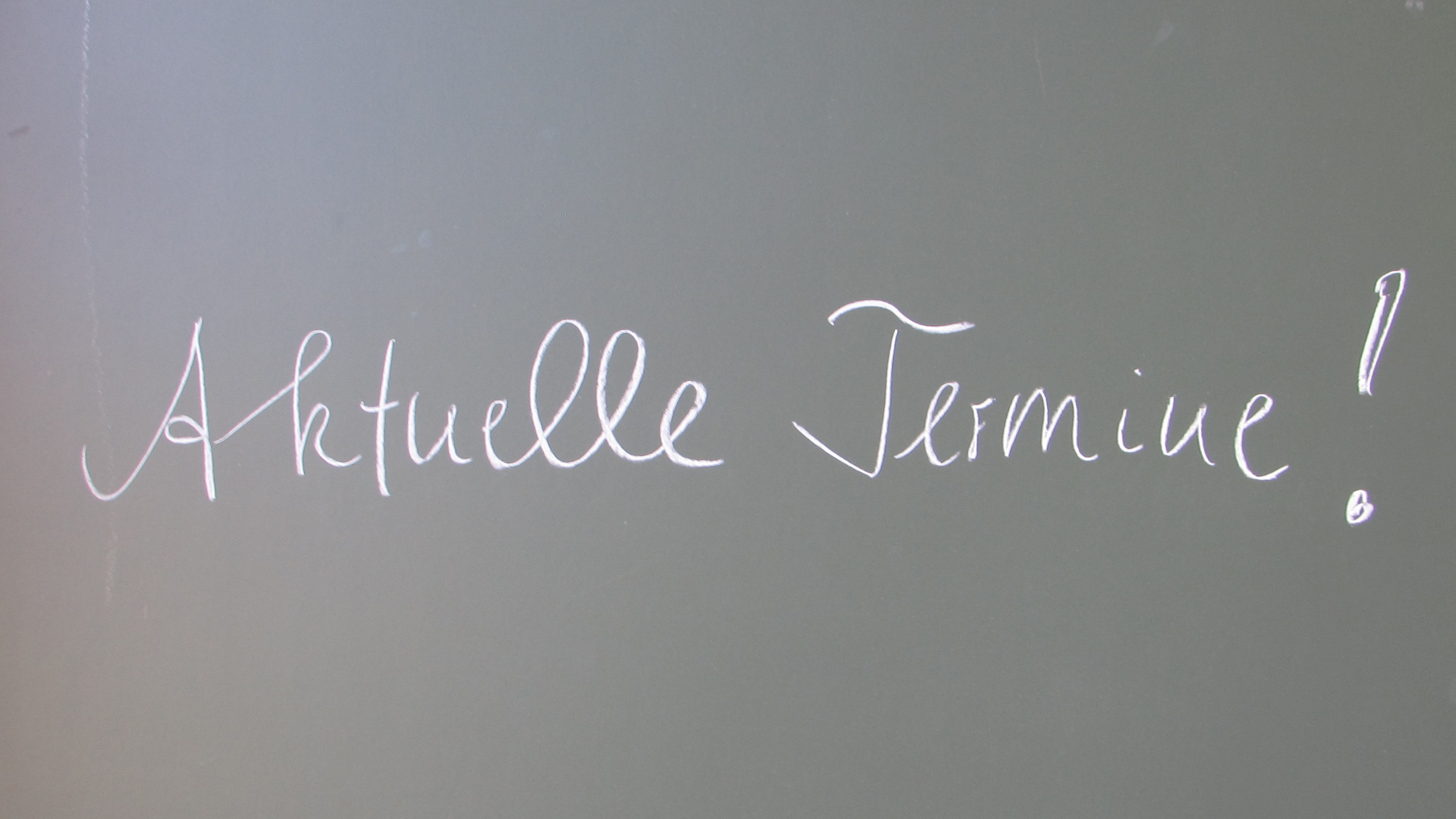 Schriftzug Aktuelle Termine mit weißer Kreide auf Schultafel 
