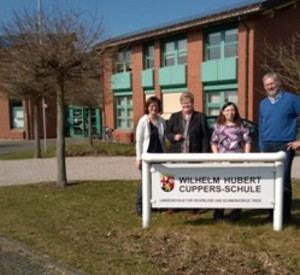 4 Personen hinter dem Schulschild der WHC-Schule.
