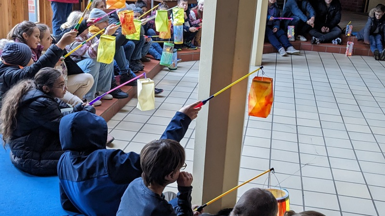 Alle Kinder zeigen ihre Laternen im Foyer. Kinder sitzen auf dem Boden.