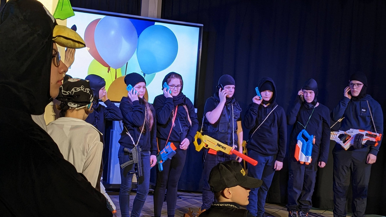 Schüler*innen führen einen Sketch auf mit Handys in der Hand. 