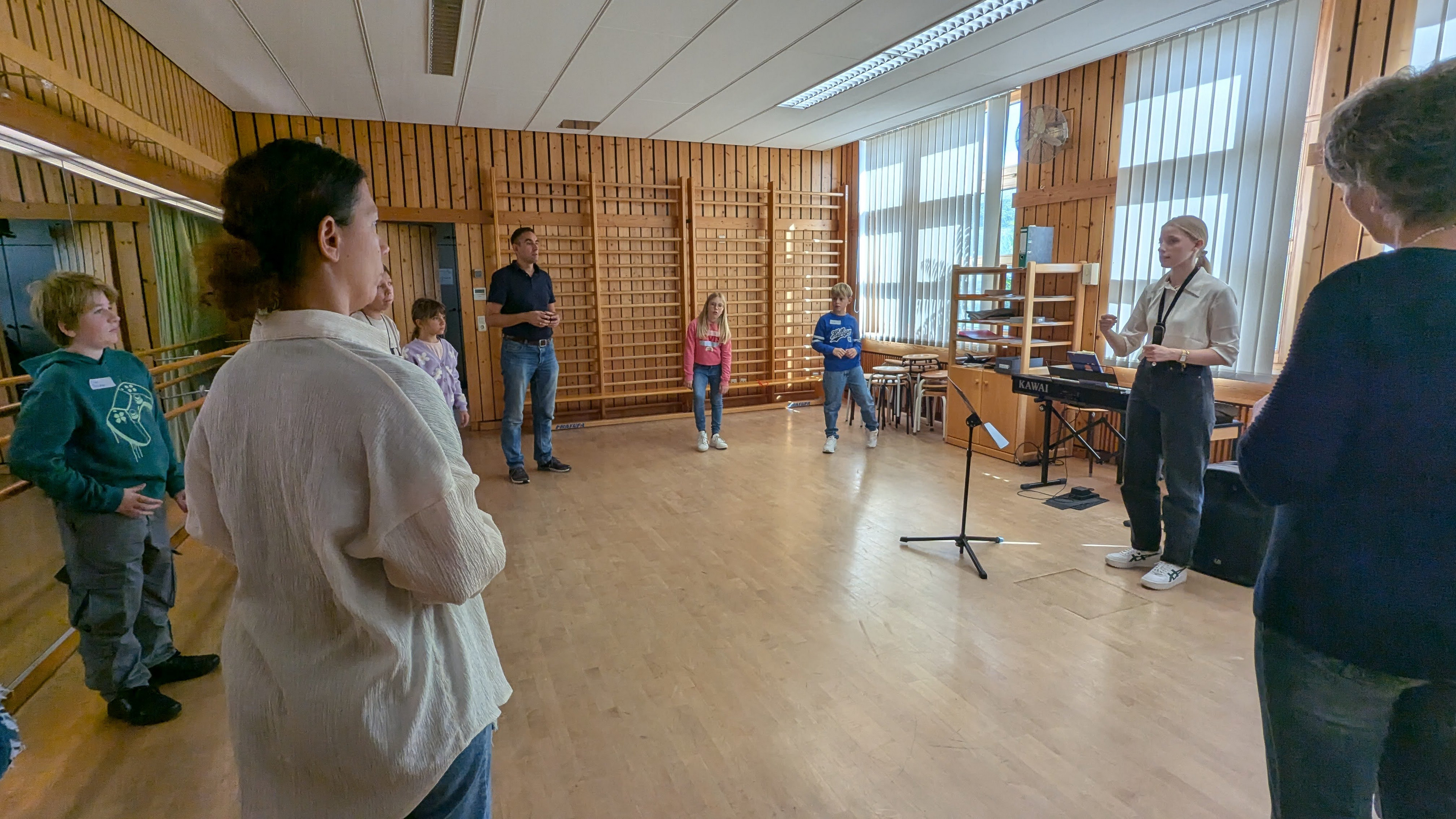 Eltern und Kinder performen mit Hand- und Körpergebärden zu einem Musikstück im Rhythmikraum. 