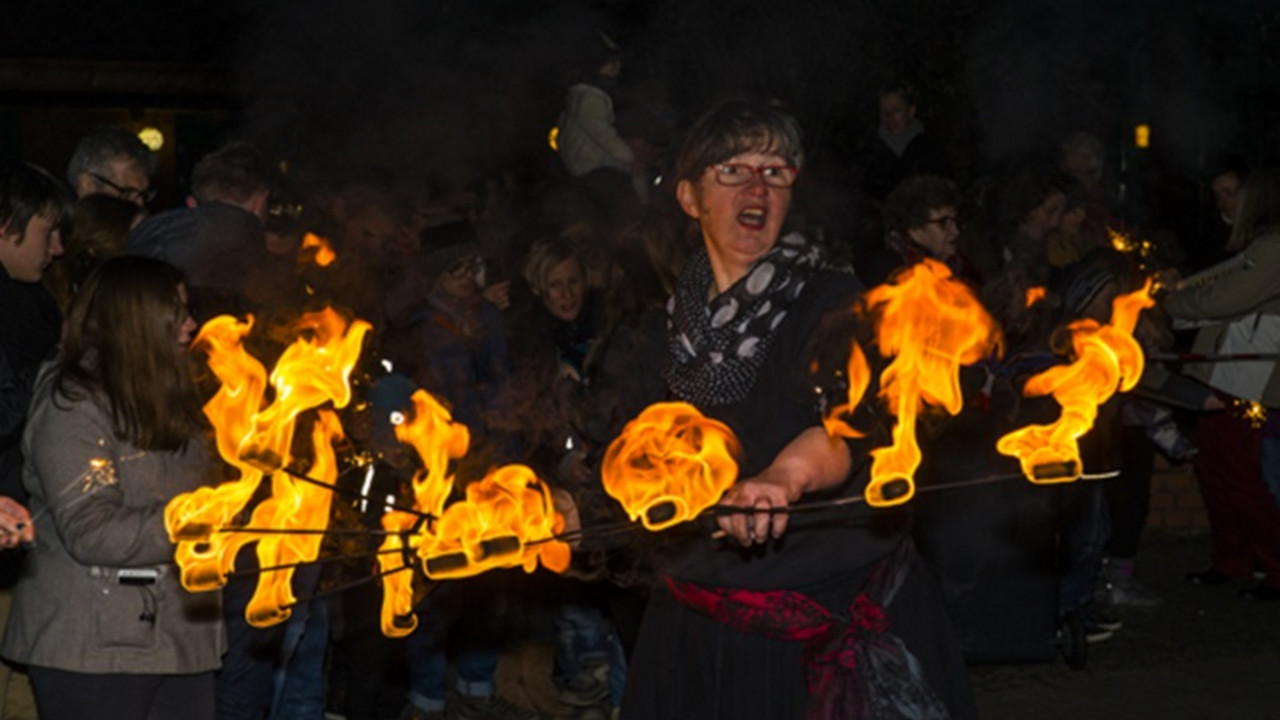 Eine Frau schleudert mehrere Feuerstäbe in der Luft. 