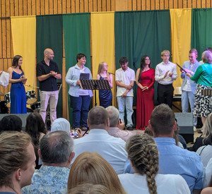 Entlassschülerinnen und Schüler mit Lehrkräften bei der Zeugnisvergabe auf der Bühne. 