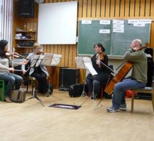 4 Orchestermitglieder mit ihren Instrumenten im Musikraum