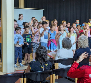 Schülerinnen und Schüler des Unterstufen-Chores singen und gebärden auf der Bühnung zum Abschied. 