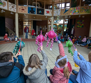 Schülerinnen und Schüler halten ihren Laternen hoch im Foyer der WHC. 