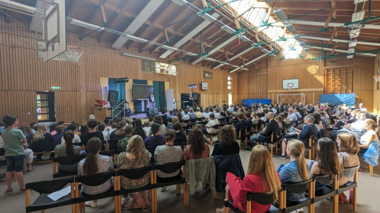 Gäste und Schüler*innen in der Turnhalle.