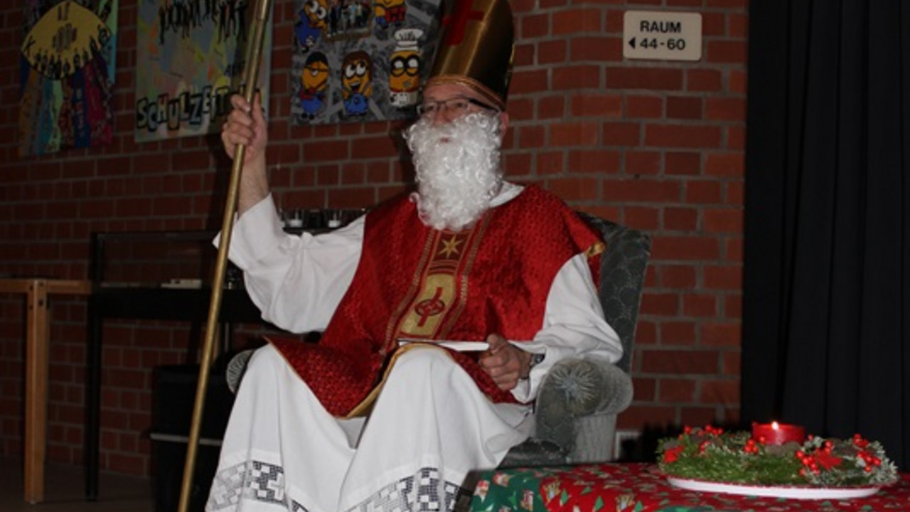 Nikolaus sitzt auf einem Sessel und schaut zu