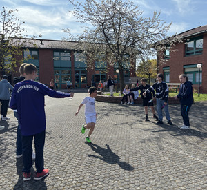 Ein Schüler wird beim Lauf von anderen Schülern angefeuert. 