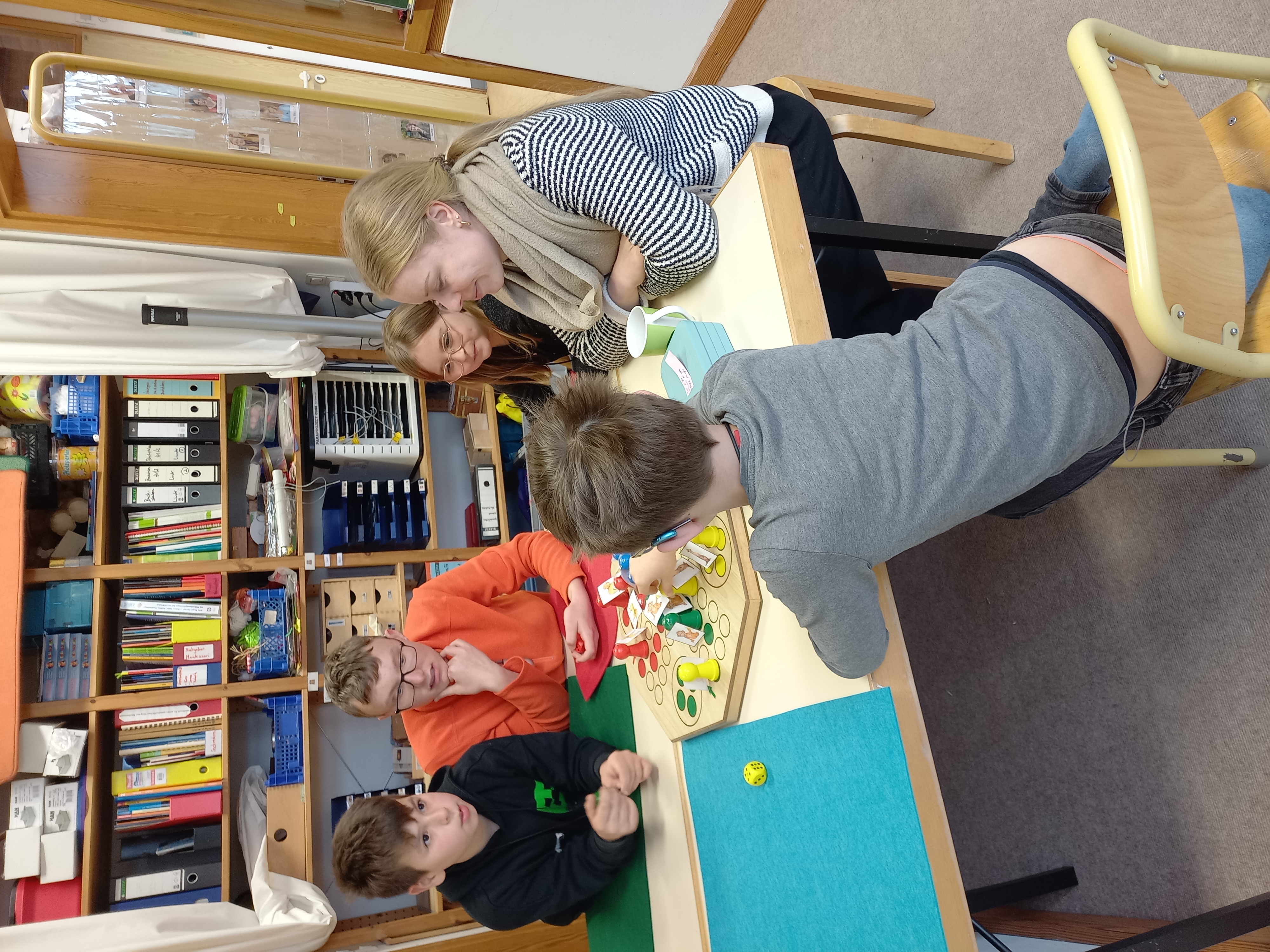 Schüler spielen Mensch-Ärgere-Dich-Nicht am Tisch.