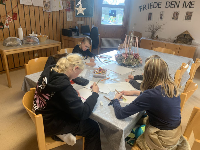 Kinder malen am Tisch.